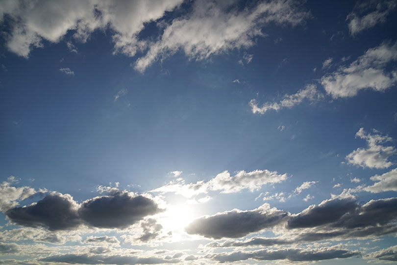 Blue sky and the bright sun blocked by cotton-like clouds.